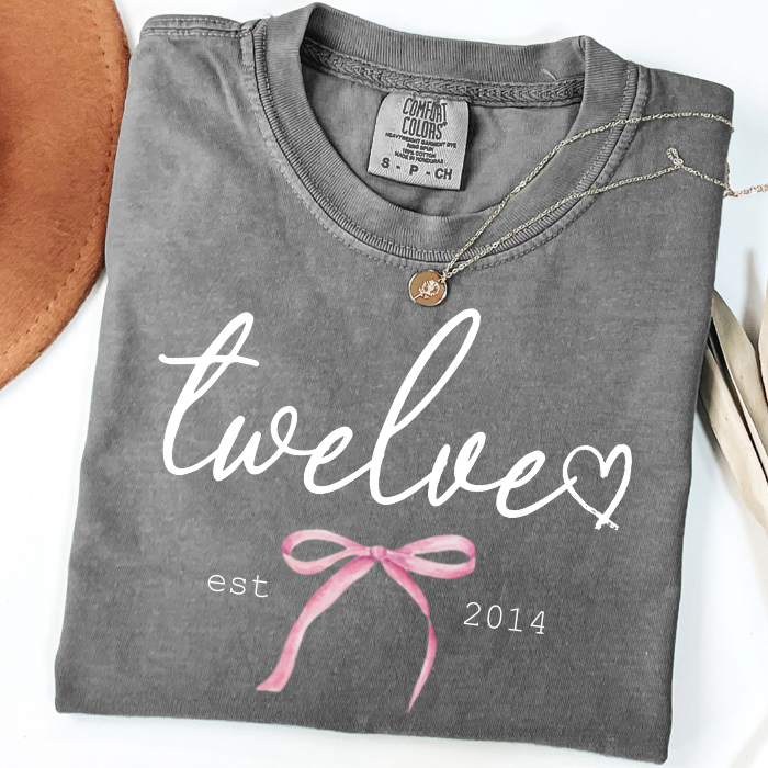 Gray Comfort Colors 12th birthday shirt with Twelve script, pink bow, and Est. 2014 design for girls celebrating their milestone birthday