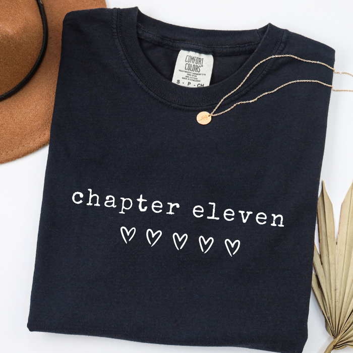 Black Comfort Colors 11th birthday shirt for girls featuring clean white Chapter Eleven typography design