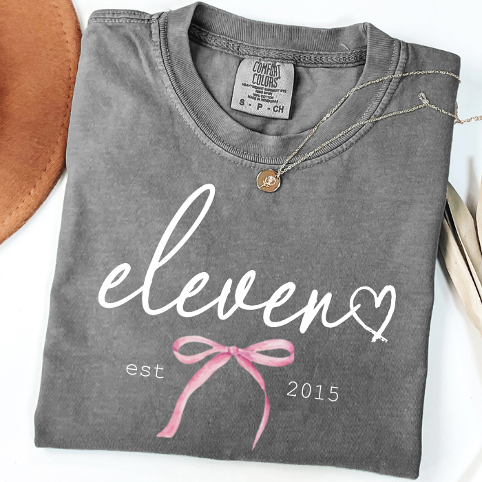Gray Comfort Colors 11th birthday tee featuring minimalist eleven script design with delicate bow detail