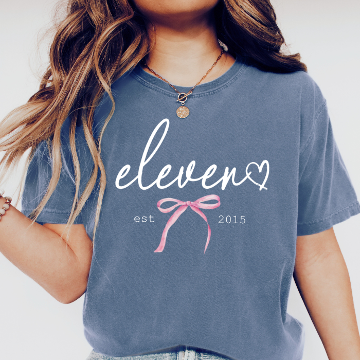 Girl wearing blue Comfort Colors eleven birthday shirt with feminine script design for an 11th birthday celebration