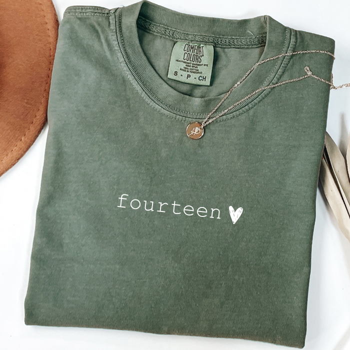 green comfort colors shirt that says fourteen with a chalk heart