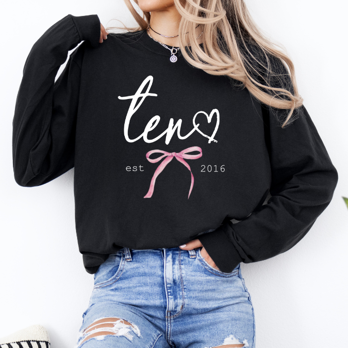 model wearing black sweatshirt with ten est 2016 coquette bow design